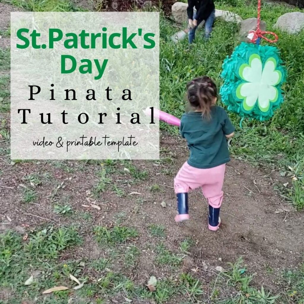 4 leaf clover pinata for st patricks day being hit by a toddler girl with a pink bat