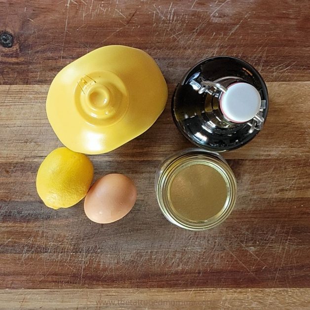 homemade mayo ingredients: organic mustard, 100 percent pure avocado oil, fresh lemon juice, Himalayan sea salt, and a farm fresh egg displayed on top of a wooden cutting board