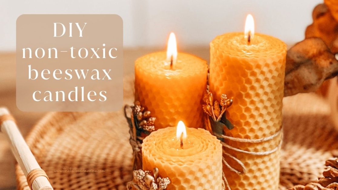 first image for the tattooedmomma.com on the blog post "How to Make Homemade easy non-toxic Beeswax Candles". image is of 3 lit orangish-yellow candles at various heights made from rolled beeswax to look like honeycomb on a shallow round woven basket tray.
